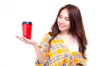 Portrait of smiling young woman standing against white background