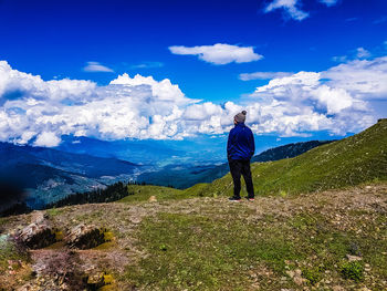 Rear view of man looking at mountain against sky