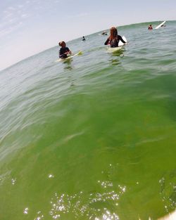People in sea against sky