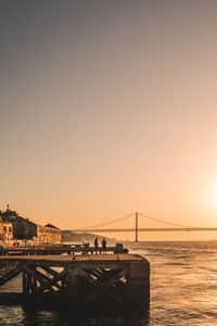 Suspension bridge over sea against clear sky