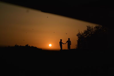 Silhouette people standing on field against sky during sunset