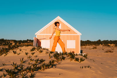 Woman walking near orange beach house.  caparica, portugal