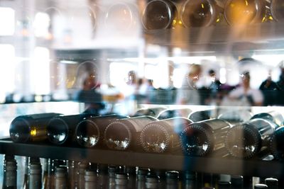 Reflection of wine in glass bottles on shelf at restaurant