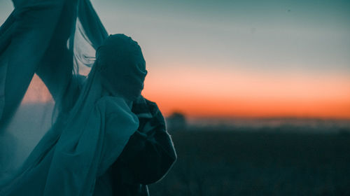 Rear view of man standing against sky during sunset