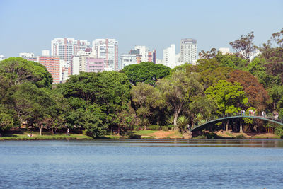 Scenic view of river by buildings against clear sky