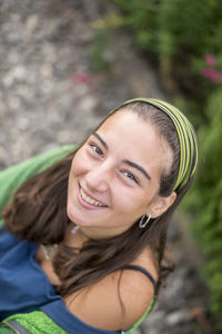 High angle portrait of smiling young woman sitting outdoors