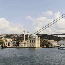 Ortakoy mosque by river against sky