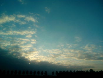 Silhouette of trees against cloudy sky