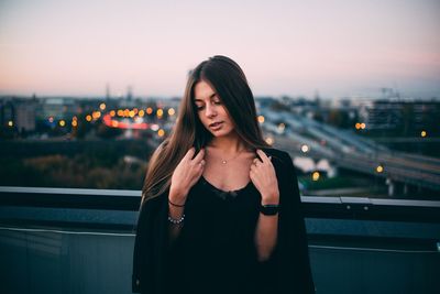 Young woman standing on illuminated city against sky