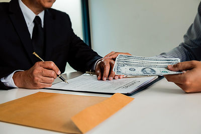 Midsection of a man holding paper