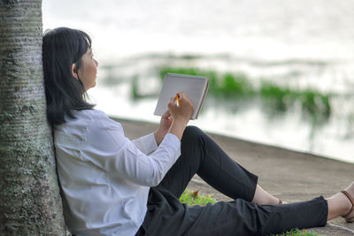 Side view of young woman using mobile phone