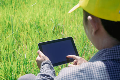 Midsection of man holding mobile phone in field