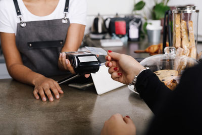 Cropped image of woman hand holding credit card while making payment in cafe