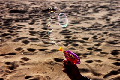 Close-up of hand holding bubbles on sand