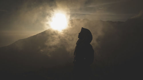 Silhouette person standing on mountain against sky