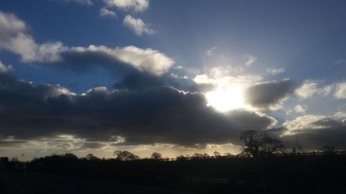 Low angle view of cloudy sky over silhouette trees