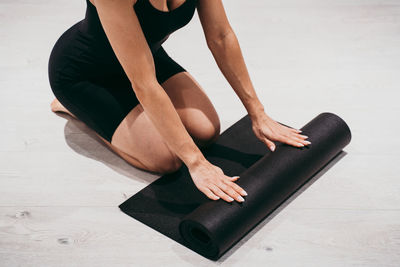 Low section of woman rolling mat at gym