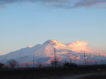 Road by mountains against sky during winter