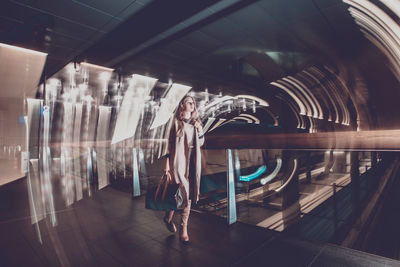 Digital composite image of woman walking in illuminated tunnel