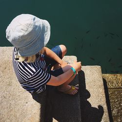 High angle view of woman in hat sitting on steps during sunny day