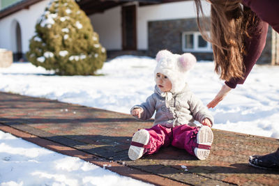 Rear view of girl sitting on snow