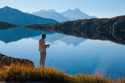 Man fishing at lake against sky