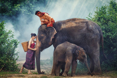 Man and woman standing by elephant