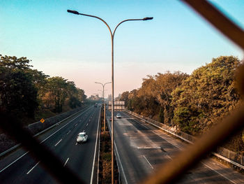 Street amidst trees against sky seen through windshield