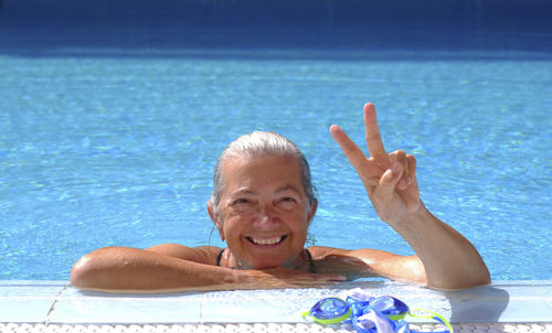 Portrait of smiling senior woman gesturing in swimming pool