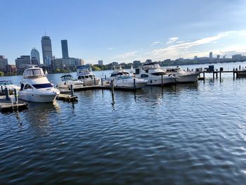 Boats moored in river by buildings against sky