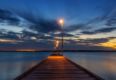 Pier over sea against sky during sunset