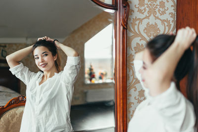 Woman with hand in hair in front of mirror at home