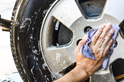 Close-up of man hand on wet car