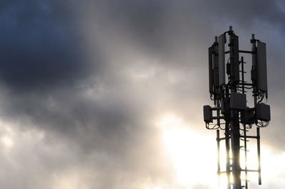 Low angle view of illuminated communications tower against sky