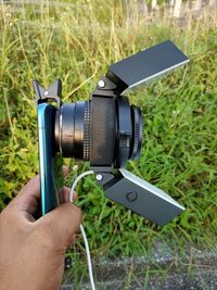 Close-up of hand holding camera on grassy field