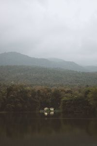 Scenic view of field by lake against sky