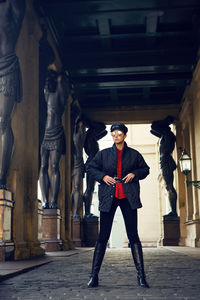 Fashionable woman in black jacket, sunglasses and red shirt stands street sculpture saint petersburg