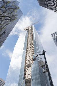 Low angle view of office buildings against cloudy sky in city