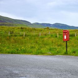 Road sign on field against sky