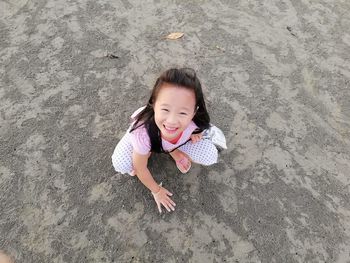 Portrait of smiling girl crouching on sand