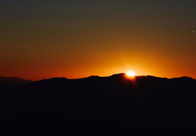 Scenic view of silhouette mountains against orange sky