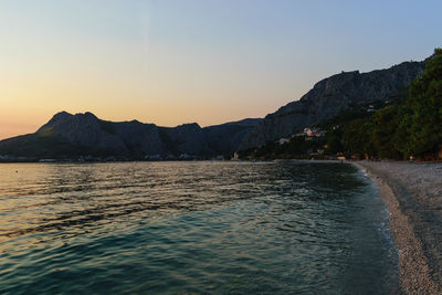 Scenic view of sea and mountains against clear sky