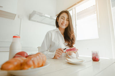 Portrait of smiling young woman having breakfast at home