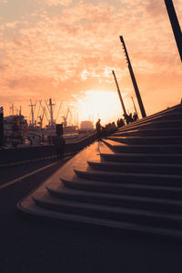 Pier at harbor against sky during sunset