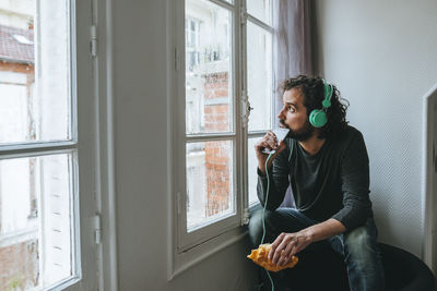 Man listening music with headphones and smartphone at home