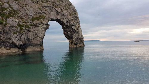 Rock formation in sea against sky