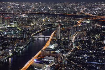 Aerial view of river passing through illuminated city at night