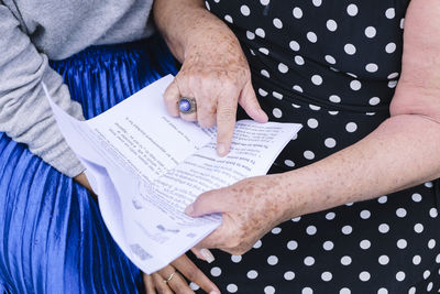 Hands of mother pointing on letter with daughter sitting at park