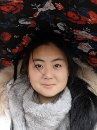 Close-up portrait of smiling woman wearing warm clothing while lying on bed at home