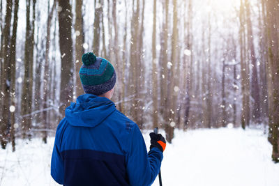 Rear view of person in snow covered forest